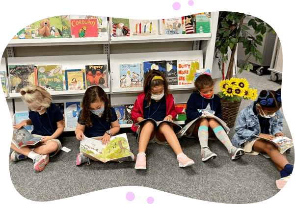 Elementary age children sitting on the floor reading books at a library