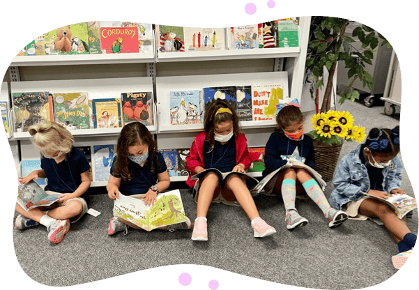 Elementary age children sitting on the floor reading books at a library